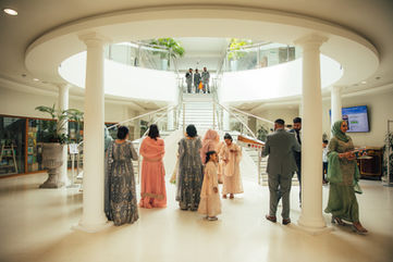 Guests gather in a bright hall, people standing by a staircase, a wedding event.