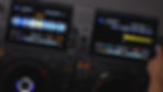 DJ equipment with dual digital displays shows waveforms and track details. A hand adjusts a knob. Vibrant blue and yellow graphics.