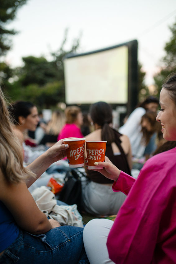 Two women toasting drinks at outdoor movie screening