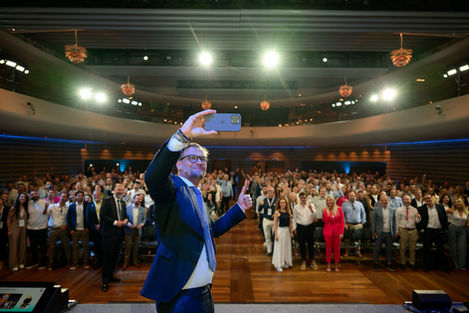 Man in suit taking selfie with large audience