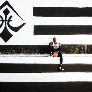 Basketball player sits against black and white wall