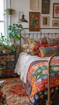 A bohemian bedroom with multicolored furniture, potted plants, and multicolored quilt bedding.