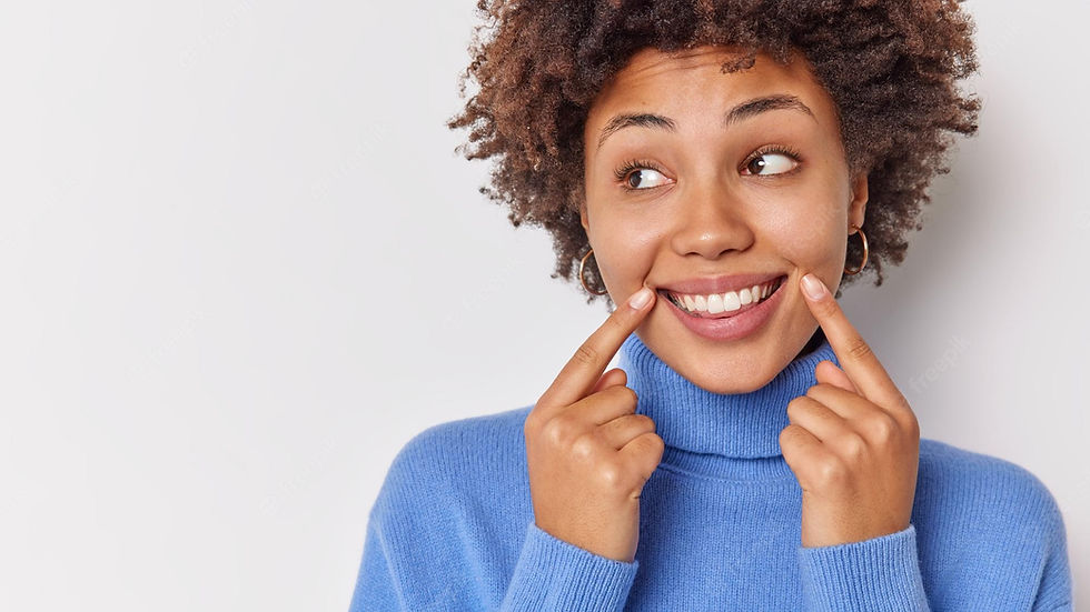 woman-smiles-broadly-points-her-perfect-even-teeth-indicates-corners-lips-looks-away-wears