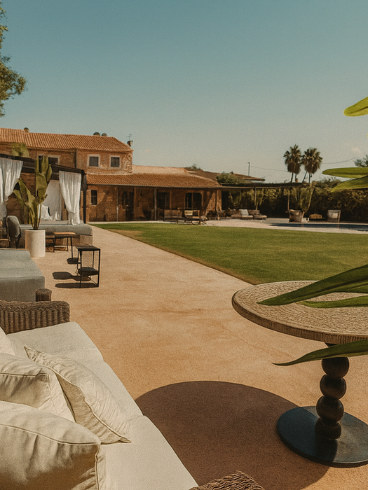 Wide view of Can Ferragut garden with outdoor sofas, shaded pergola lounge, green lawn, and pool area in the background – Mallorca villa rental.