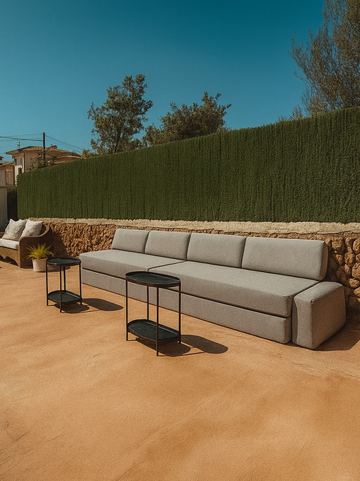 Large outdoor patio with long gray sofa, wicker lounge chairs, side tables, and stone wall backdrop – Can Ferragut Mallorca.
