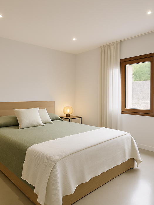 Modern Mediterranean bedroom with wooden bed, green bedspread, bedside tables with lamps, and large window – Can Ferragut Mallorca.