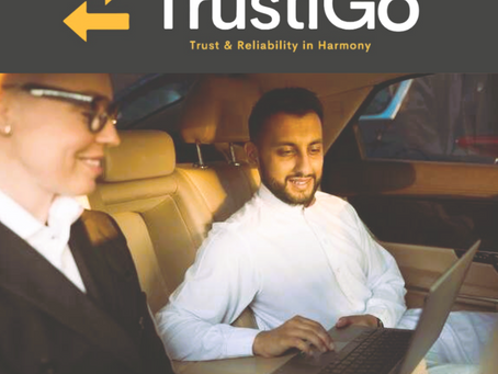 Two people in a car, one using a laptop. Text: TrustiGo, Trust & Reliability in Harmony. Warm lighting and professional attire.