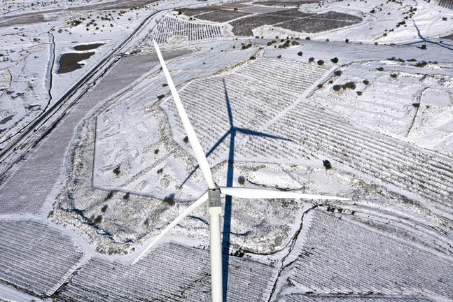A turbine of the Emek Habacha (Valley of Tears) wind energy project towers over snow-covered vineyards and orchards near Kibbutz El Rom in Israel's Golan Heights.