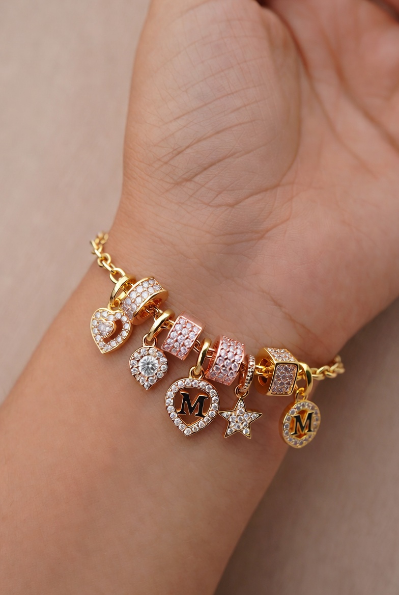 Gold charm bracelet with heart and star pendants on wrist