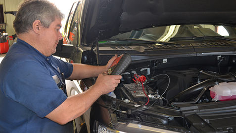 Mechanic checking a car battery with a meter at a repair shop