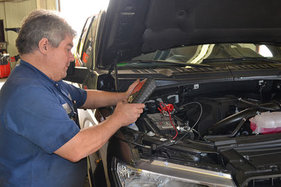Mechanic checking a car battery with a meter at a repair shop