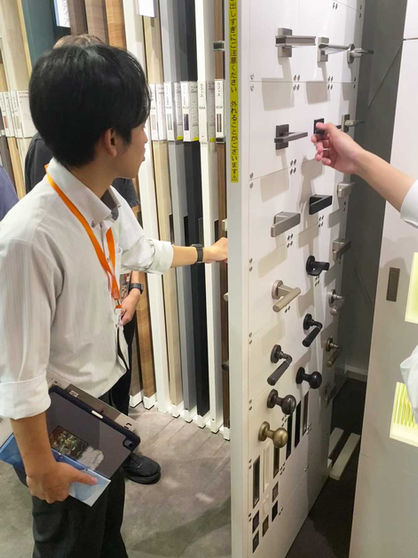 ドアノブのサンプルを見る新入社員