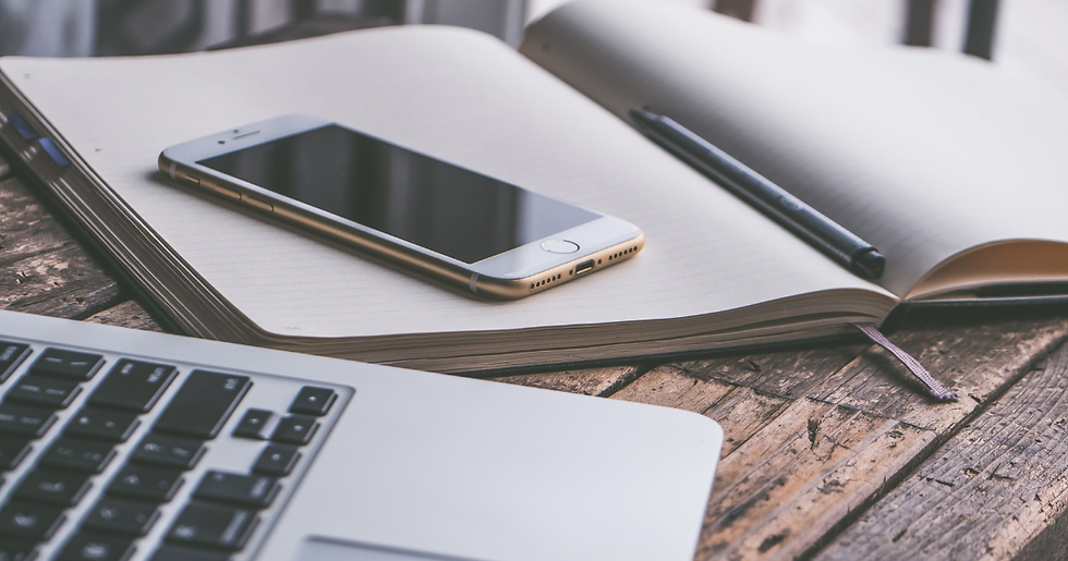 laptop, phone and an open notebook on a table