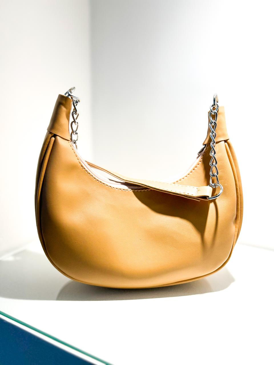 Miniatura: Bolsa de ombro feminina bege (nude) com textura em formato meia-lua, com alça de corrente prateada.