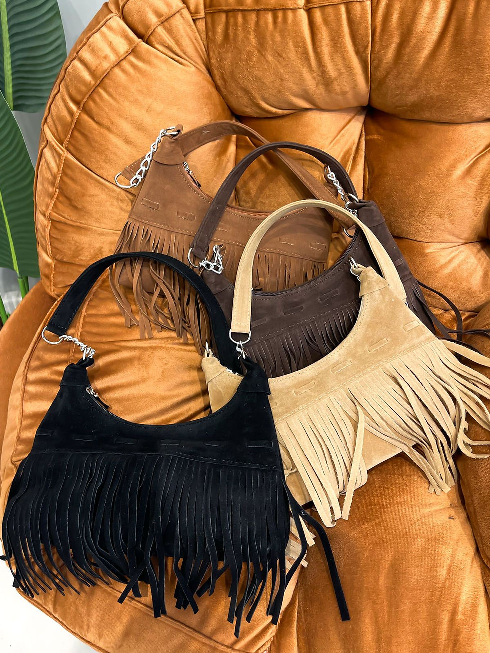 Quatro bolsas de ombro meia-lua em camurça com franjas longas nas cores: preta, bege, marrom e marrom-escuro.