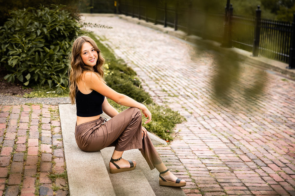 senior portrait of a girl wearing a crop top and brown pants while sitting on brick stairs