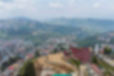 Hilly environment with lush green forests and misty skies.
