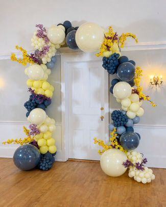 Luxury doorway balloon arch with navy and yellow balloons and coordinating florals