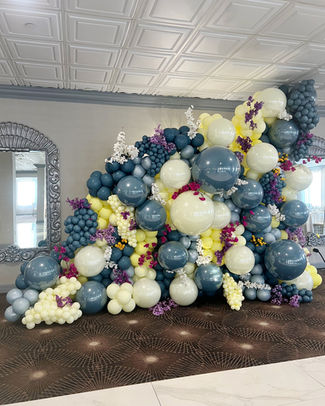 Angled organic balloon wall 12x12 featuring oversized balloons, layered mini clusters and decorative floral accents.