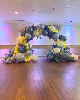 Luxe Classic Arch with full organic balloon garland and floral accents on a freestanding arch frame