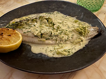 Fish on a black plate with a creamy sauce on top