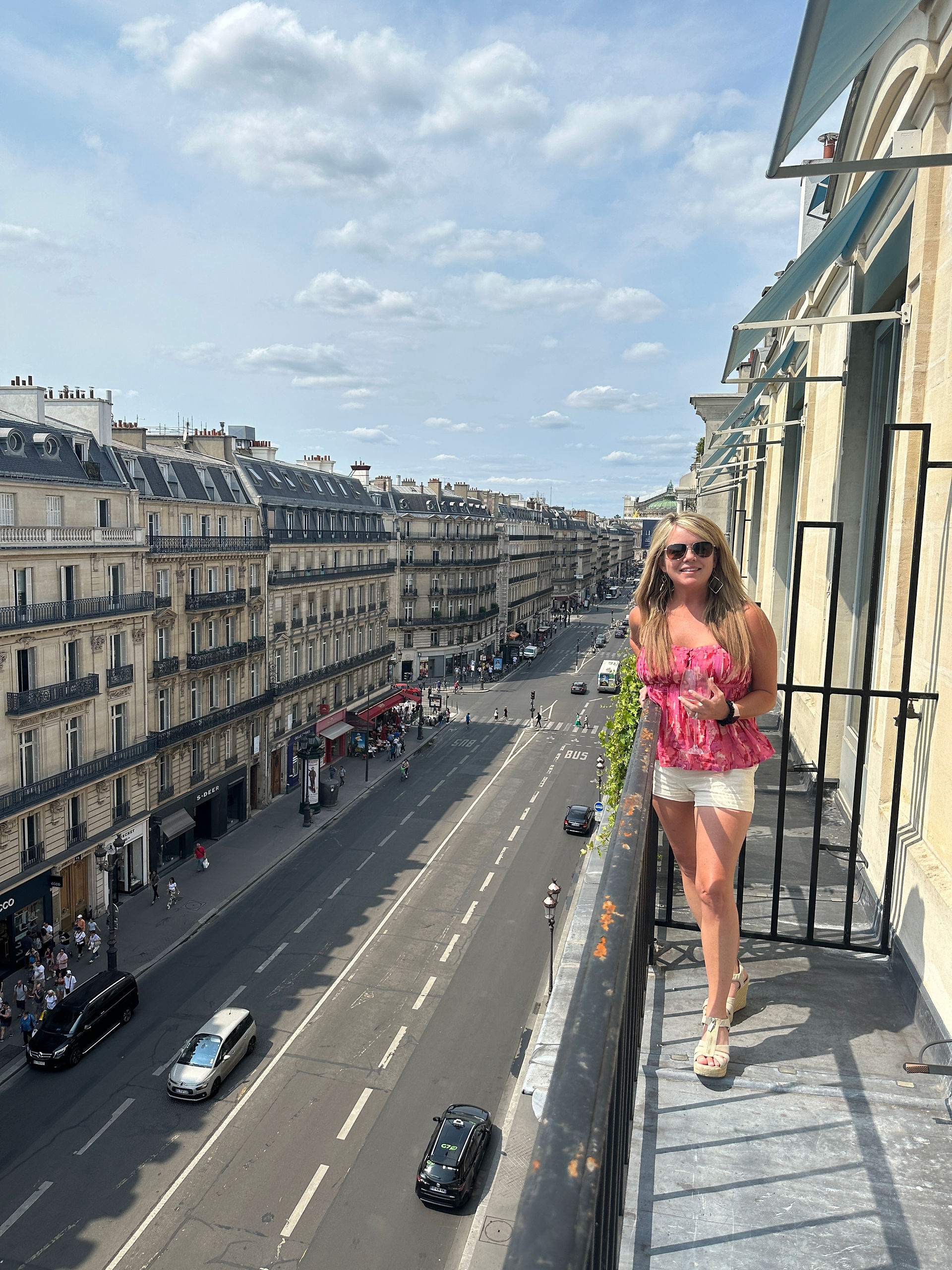 Woman standing on a narrow balcony overlooking a street in Paris at the Nolinski Paris
