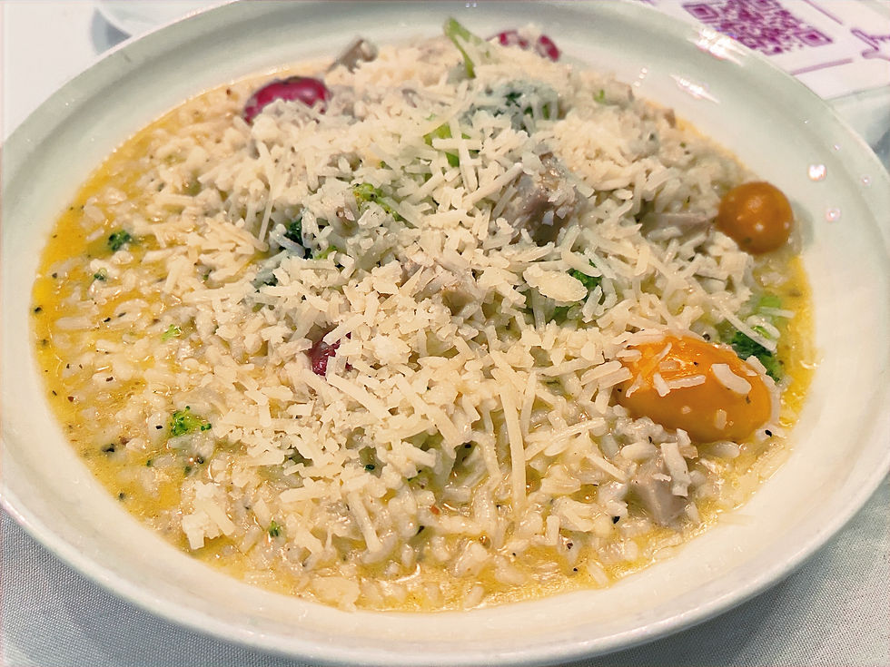 Risotto dish in a white bowl topped with parmesan and cherry tomatoes