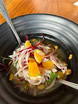 Ceviche in a bowl with orange slices on top and a spoon in the bowl