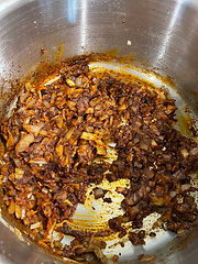 Stainless stee pot with spices and onions browning in a pan