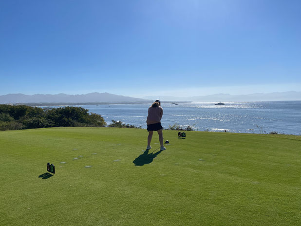 Girl teeing off on a tee box that overlooks the ocean