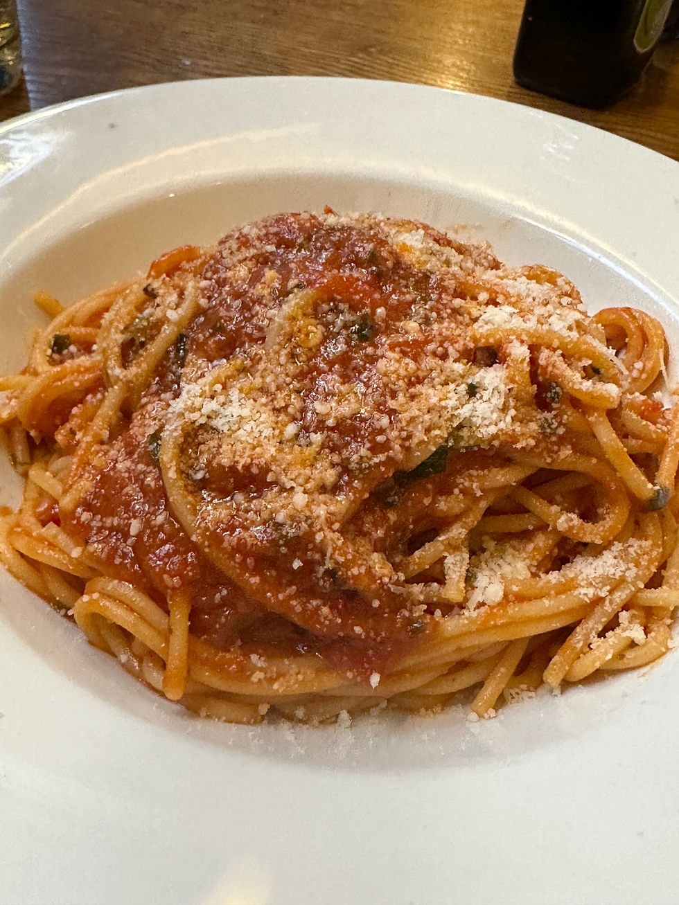 White bowl with spaghetti and red sauce with parmesan 