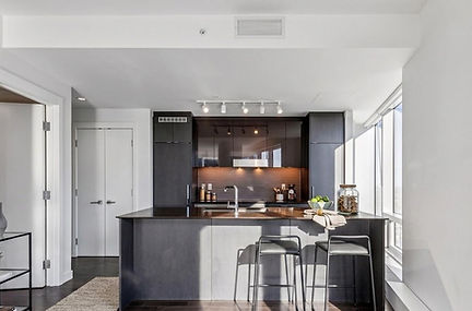 Edmonton Ice District high-rise kitchen view with light furnishing complimenting dark wood cabinets and flooring. 