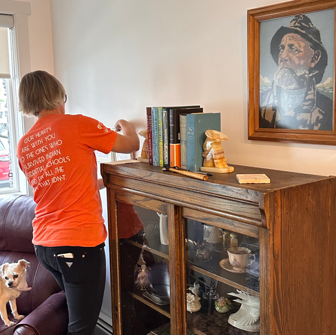 A Sort & Simple professional organizer hanging favorite framed artwork on the wall of a newly moved senior client.