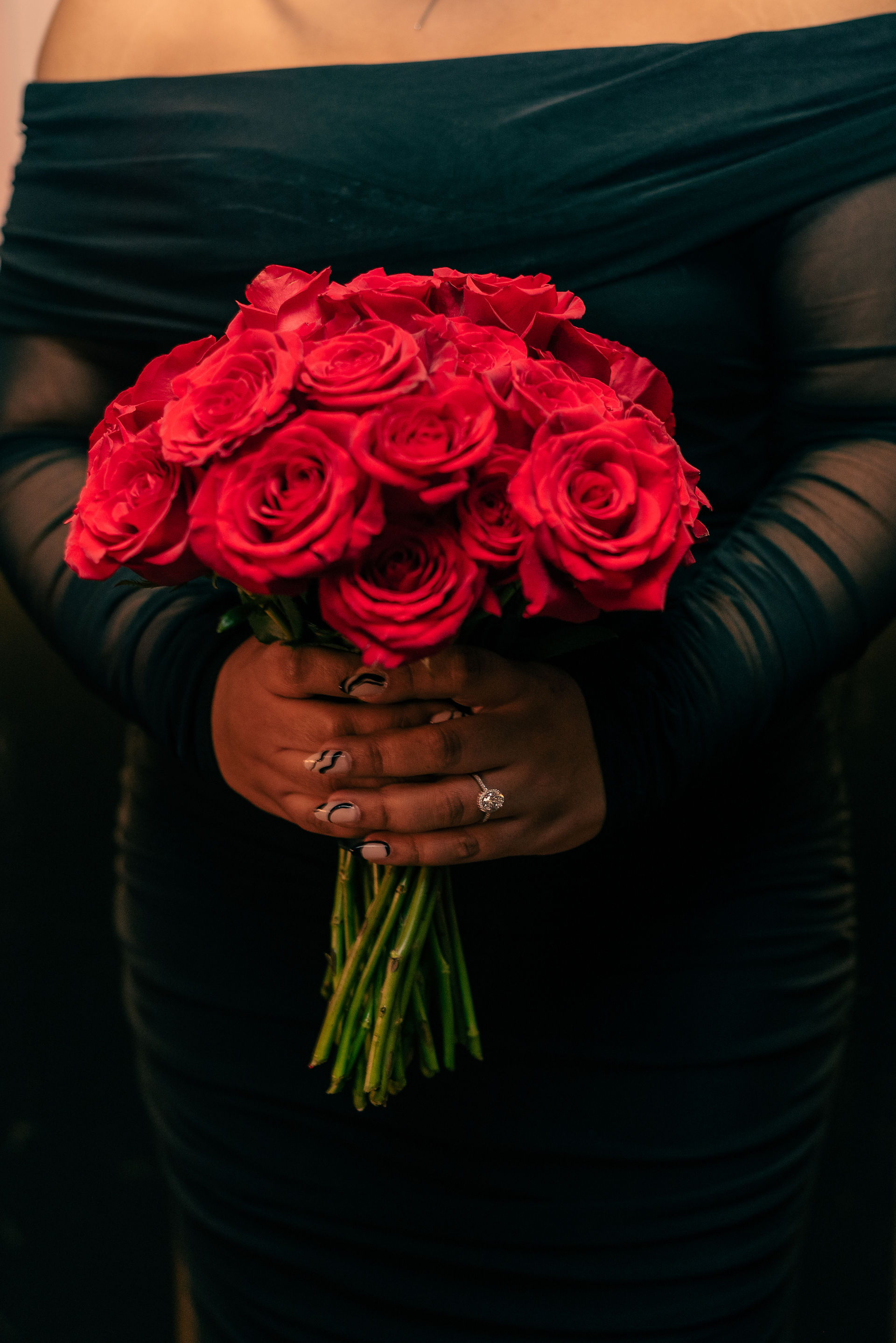 woman holding a rose bouquet with the focus on her hand with an engagement ring for a proposal; valentine's day proposal ideas
