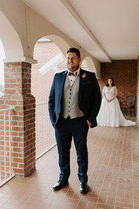 bride standing behind groom; groom and bide about to do first look session of the wedding day timeline