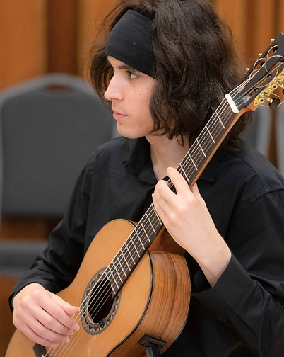 Mr. Daniel de la Cruz, guitar instructor at Brownsville Piano Studio, seated in a music studio, Brownsville, TX