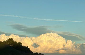 An image of puffy clouds on the horizon at golden hour.