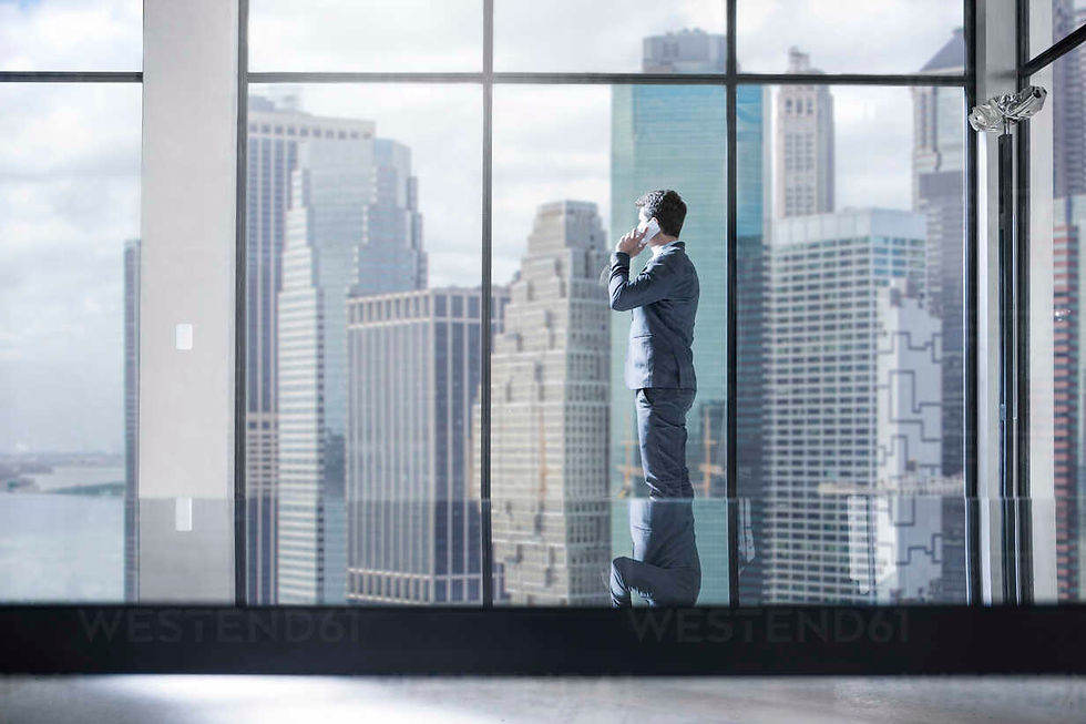 businessman-on-the-phone-in-city-office-looking-out-of-window-ZEF13648.jpg