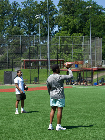 Coaches standing on baseball field teaching football drills. 