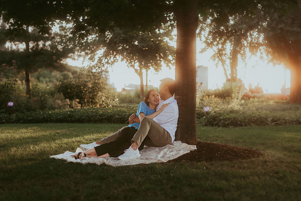 A couple lounging together under a tree during golden hour at their engagement session in Ottawa, Ontario.