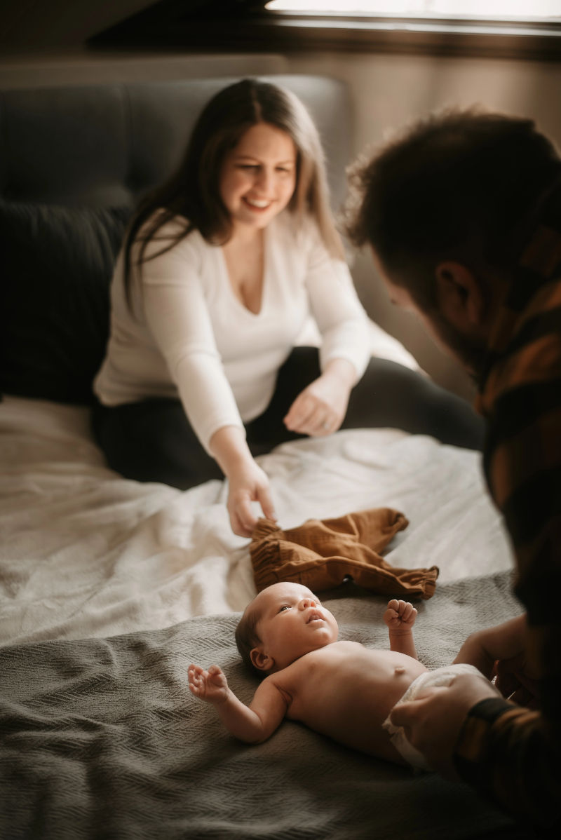A new mother looks on as her new baby is being changed by her husband.