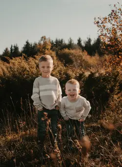 Two young brothers smiling in field.