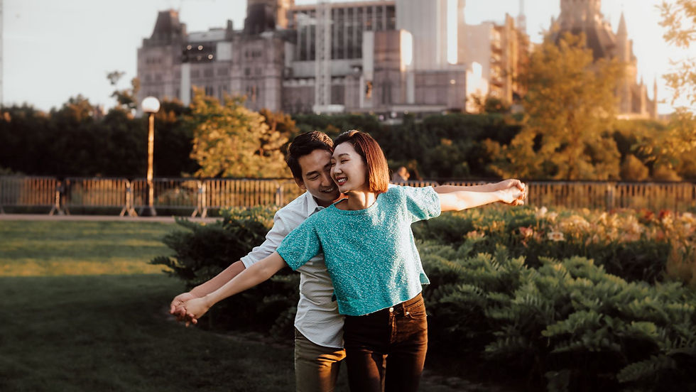 A young couple laughing during their engagement session in Ottawa, Ontario, by the Parliament Buildings.