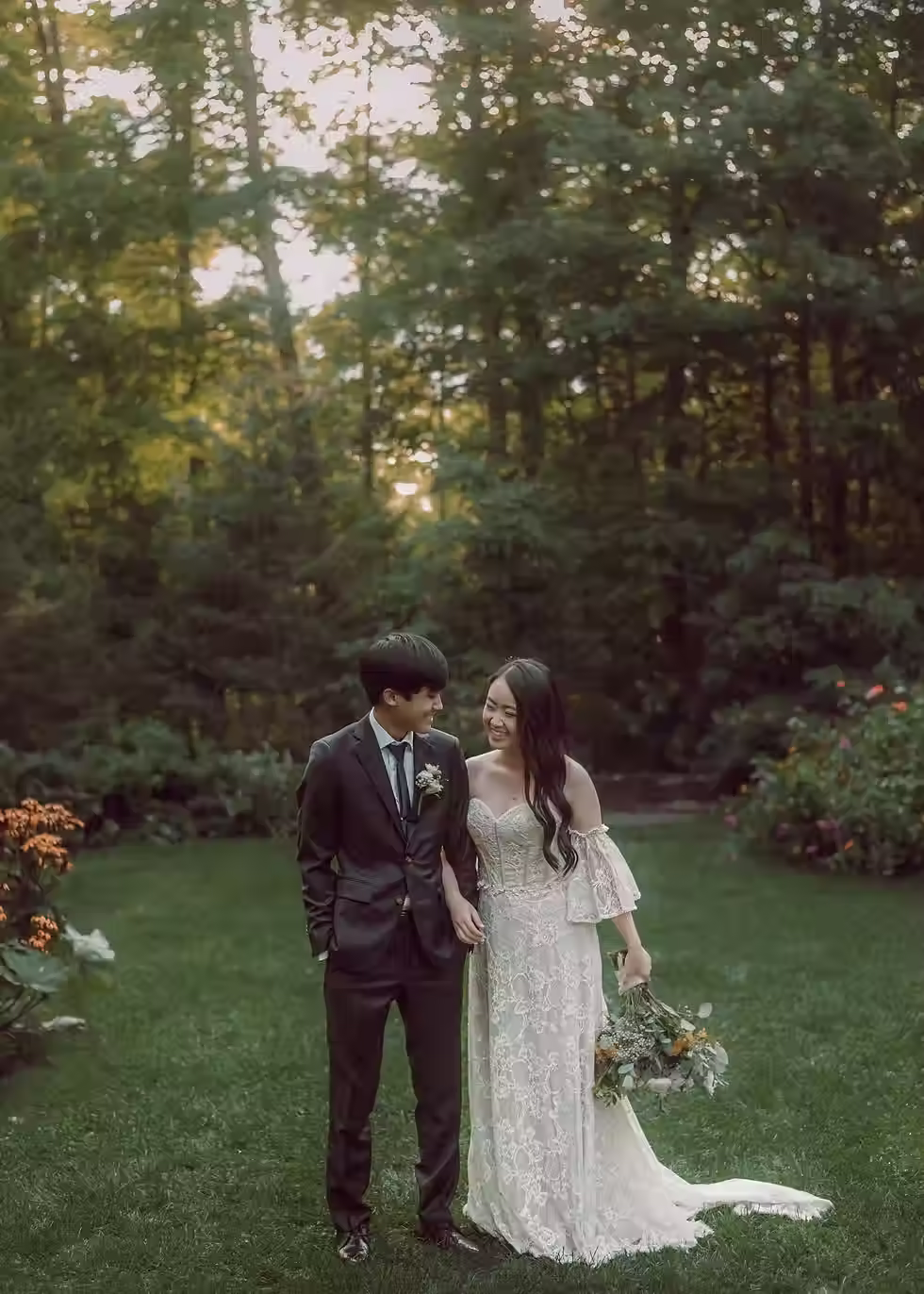 A bride and groom walk together in a beautiful garden during golden hour, after their Ottawa wedding ceremony.
