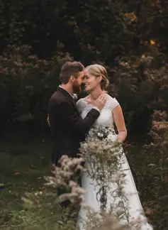 Bride and her groom embracing in a field of wild flowers.