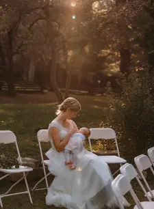 A bride nursing her baby during golden hour.