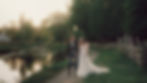 Couple walking hand in hand down a tree-lined path at sunset, surrounded by warm golden light and greenery.