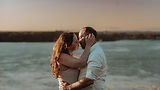 An intimate, documentary-style portrait of a couple embracing at sunset by the water, representing moody and emotional wedding and family photography in the Ottawa Valley.