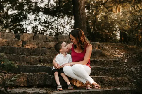 A mom hugging and talking to her young son while sitting on stone steps.
