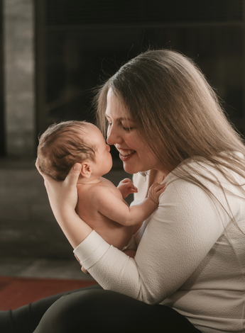 A mother smiles down at her newborn son during her in home newborn photography session in Ottawa.